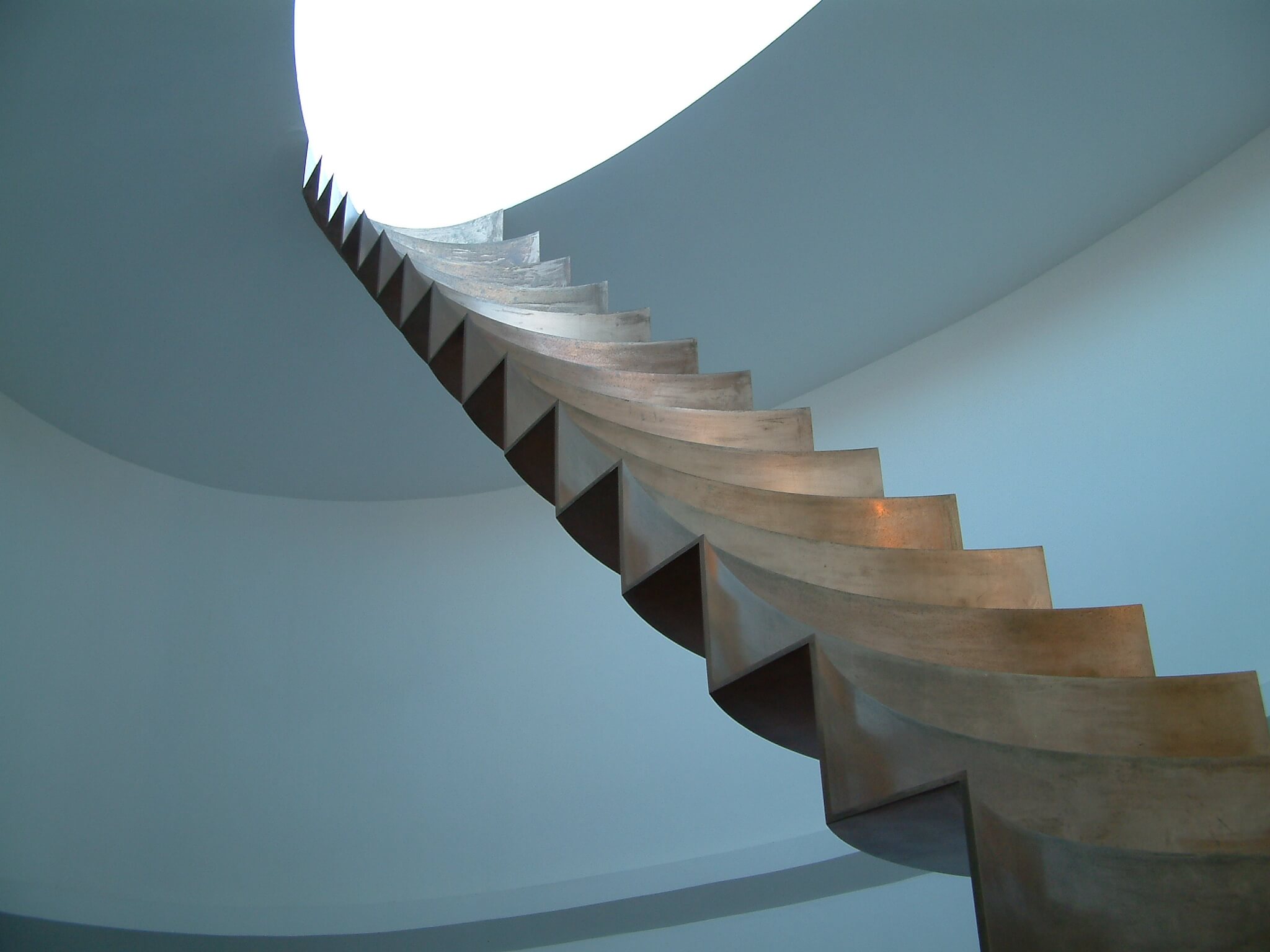 Metal stairs leading to an oval hole in the ceiling built by a design and engineering company